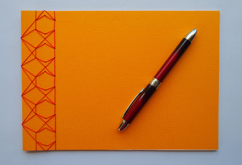 Festive special: notebooks with unique hand-bound decorative designs in rich yellow with kissing fish binding